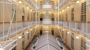 Un atrio de varios niveles con una escalera central, varios balcones e iluminación colgante.