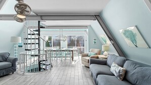 A modern loft apartment with a spiral staircase, a dining area, and a living room with a sofa and armchairs. - Mermaid’s Retreat - Heated Private Pool, Walk to Beach, Complimentary Bikes! (Santa Rosa Beach)