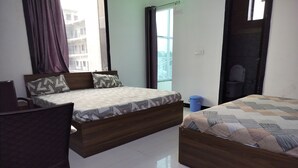 Un dormitorio con dos camas, una silla, una ventana con cortinas y vistas a edificios.