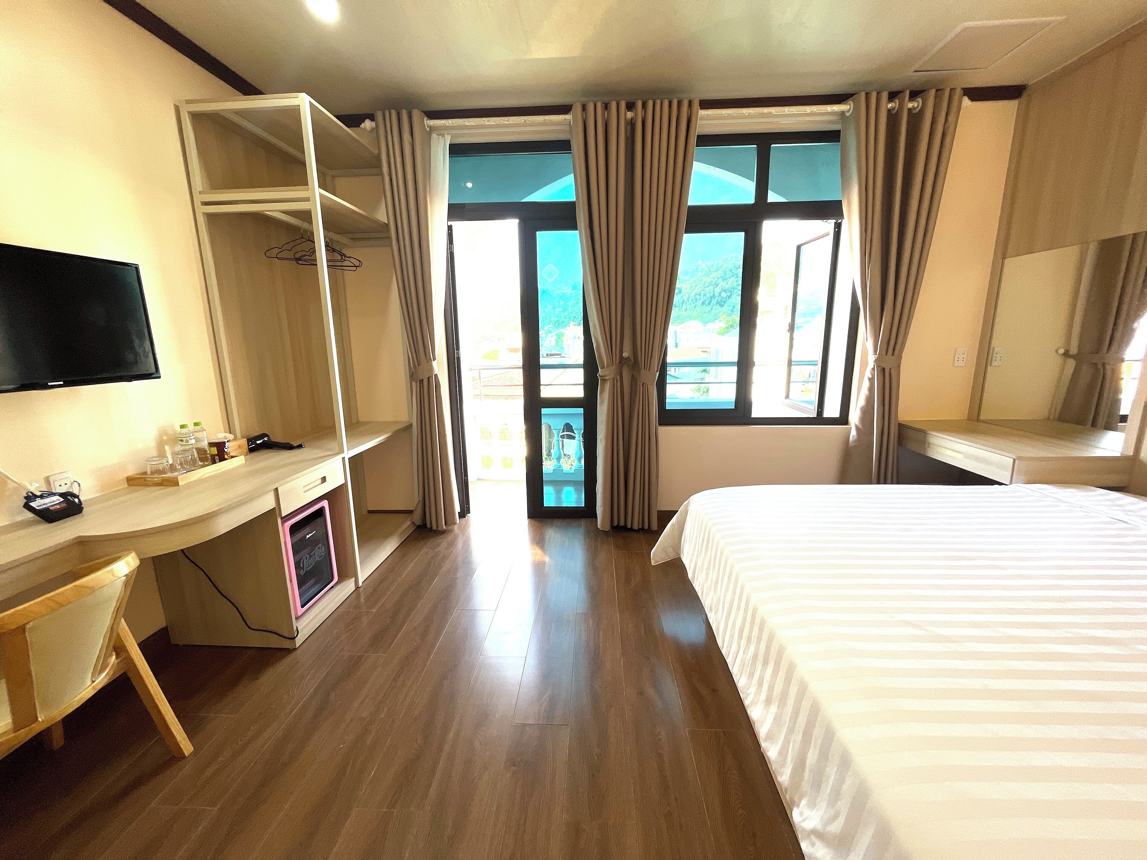 A hotel room with a bed, a desk with a computer, a TV, and a wardrobe.