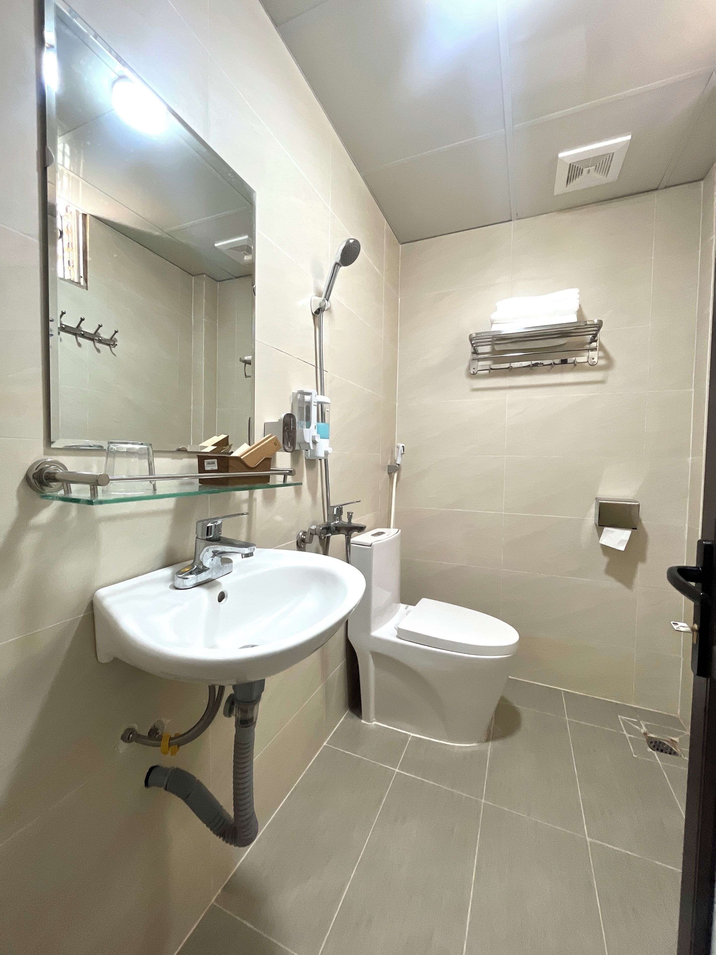 Un baño con lavamanos, inodoro y estante de vidrio.