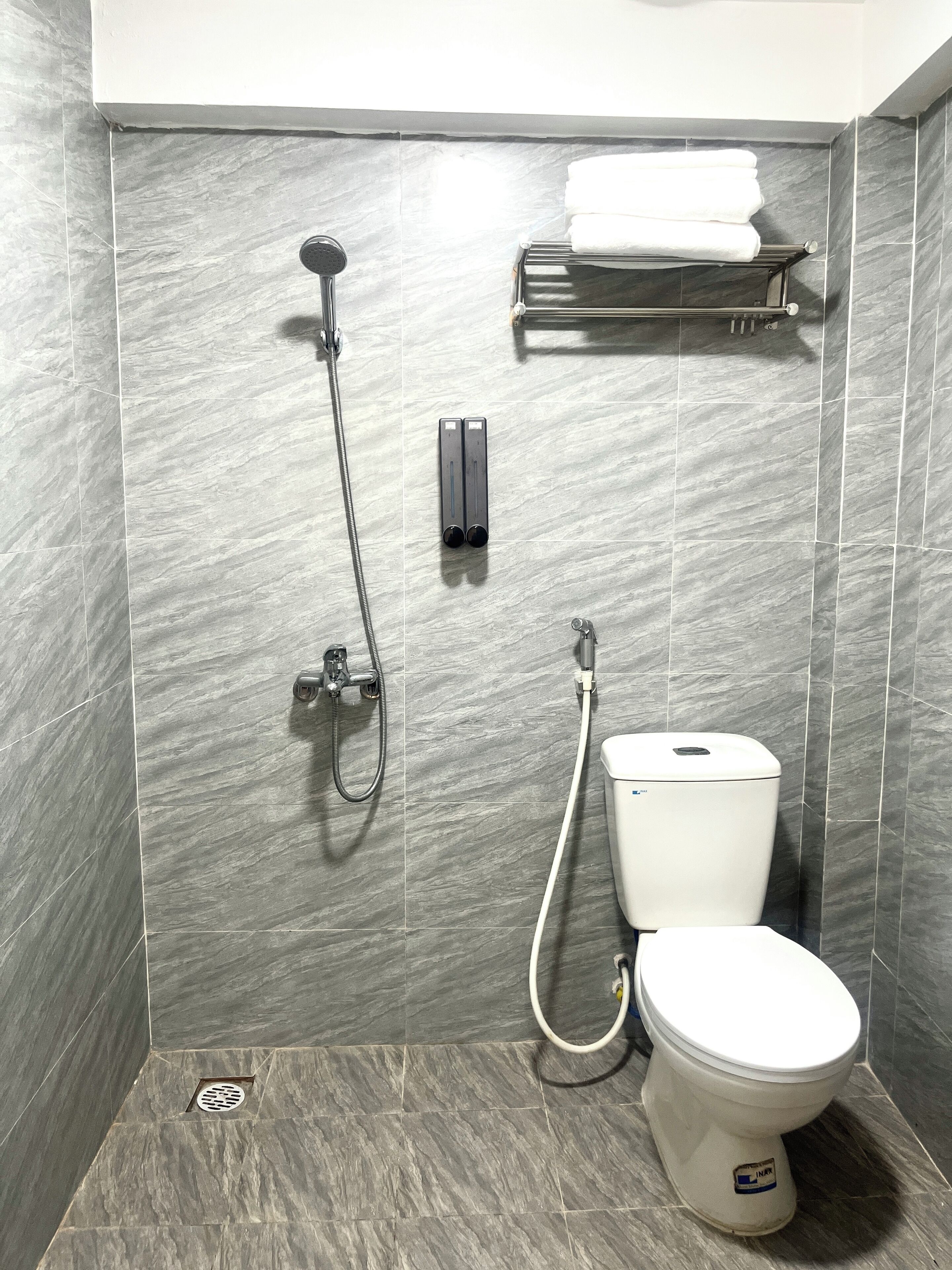 A modern bathroom with a shower, toilet, and towel rack.