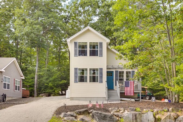 Une maison à deux étages avec un porche à l’avant et un drapeau.