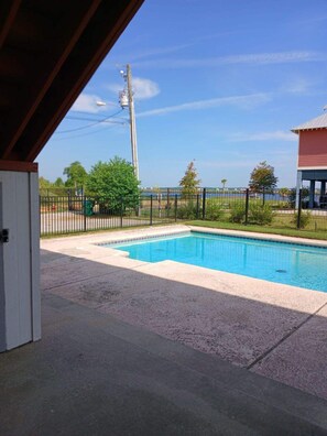 Une piscine avec vue sur une étendue d’eau et un bâtiment situé au loin.