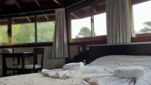 Hotellihuone, jossa on sänky, tuoli ja pöytä.