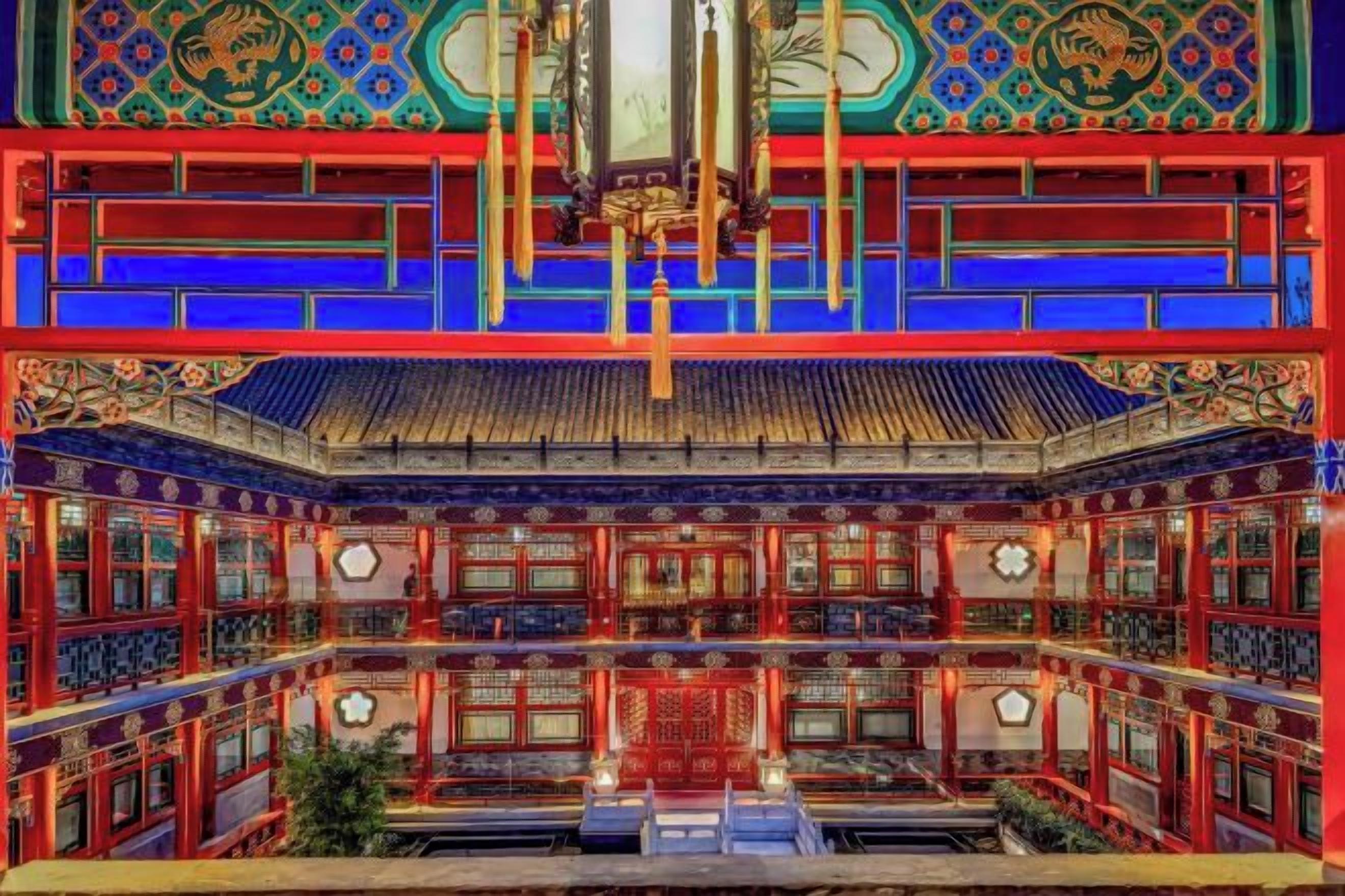 Un edificio tradicional chino con decoraciones ornamentales en rojo y azul, techo de tejas y un patio central.