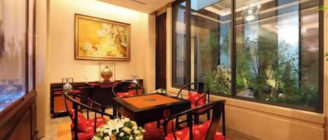 A dining area with a table and chairs, a vase of flowers, and a painting on the wall.
