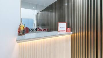 A reception desk with a RedDoorz sign, a framed notice, and a statue.