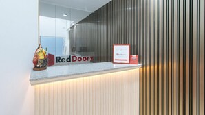 A reception desk with a RedDoorz sign, a framed notice, and a statue. - Reddoorz @ St. Catherine Residences Olongapo City (Olongapo)