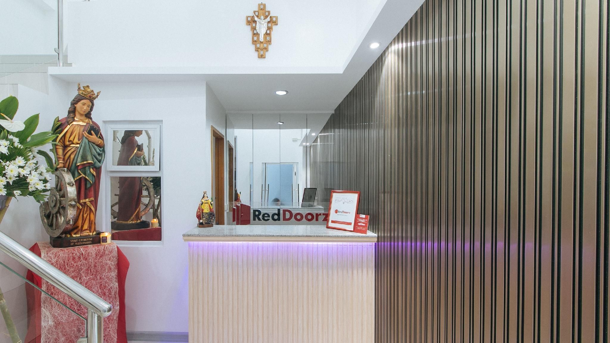 A reception area with a statue of a saint, a Red Doorz sign, and a modern interior design.