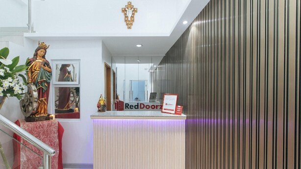 A reception area with a statue of a saint, a Red Doorz sign, and a modern interior design. - Reddoorz @ St. Catherine Residences Olongapo City (Olongapo)