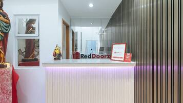 A reception desk with a RedDoorz sign, a statue, and framed pictures on the wall.