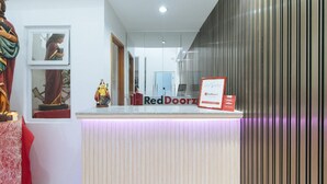 A reception desk with a RedDoorz sign, a statue, and framed pictures on the wall. - Reddoorz @ St. Catherine Residences Olongapo City (Olongapo)