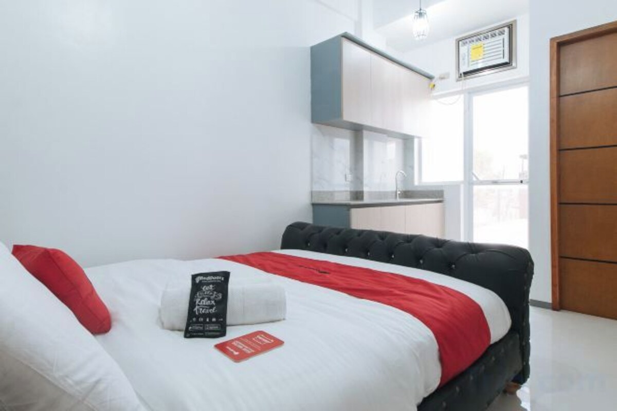 Ein Hotelzimmer mit einem Bett, einer rot-weißen Tagesdecke, einem schwarzen Kopfteil und weißen Kissen.