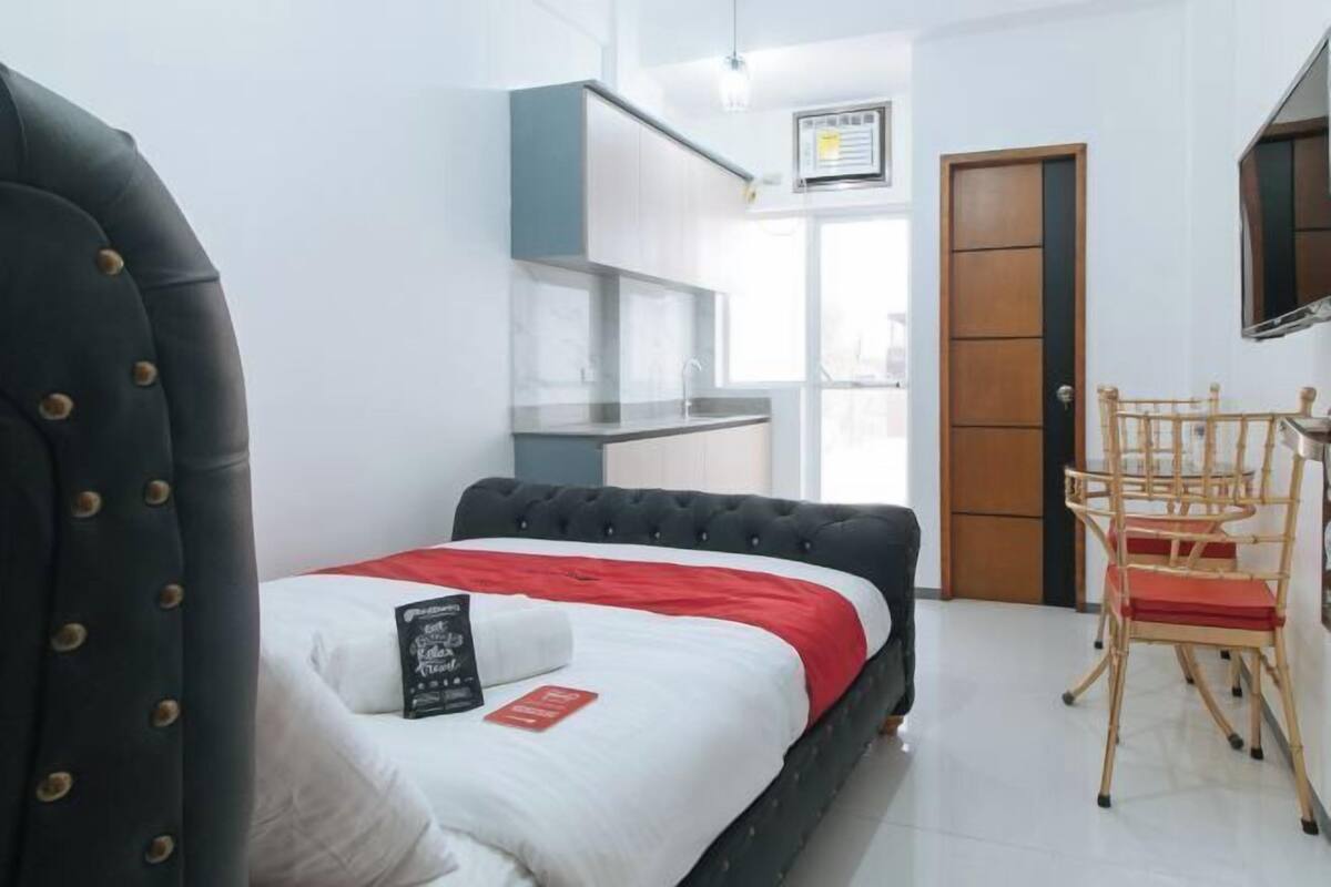 A bedroom with a bed, a desk, a chair, a wardrobe, and a window.