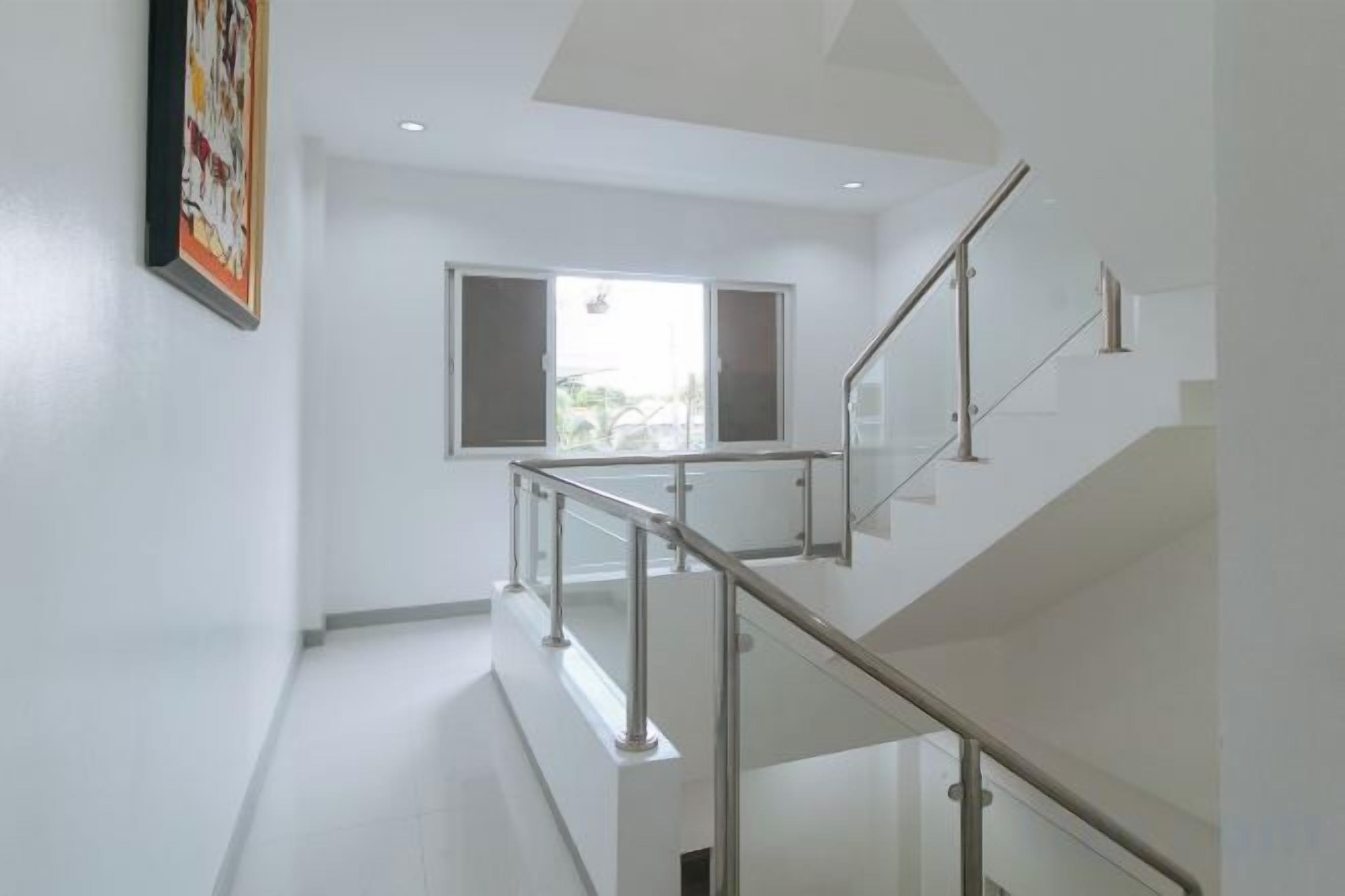 A modern interior with a staircase, a window with open shutters, and a framed picture on the wall.