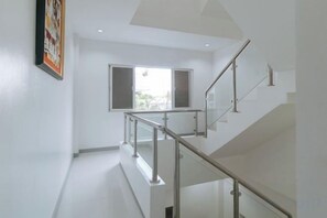 A modern interior with a staircase, a window with open shutters, and a framed picture on the wall. - RedDoorz @ St Catherine Residences Olongapo City (Olongapo)