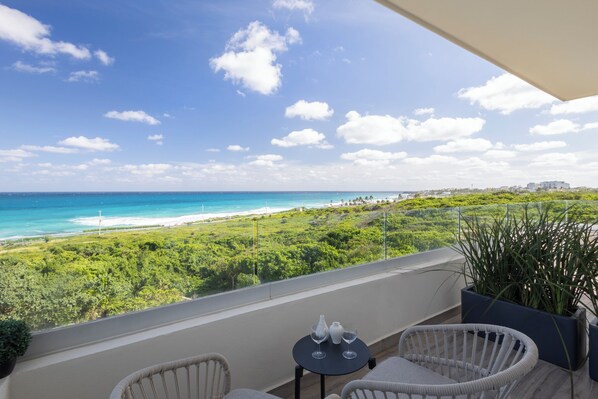 A balcony with wicker chairs and a small table, overlooking a beach and lush greenery. - Azulea Isla Mujeres Hotel & Spa (Isla Mujeres)