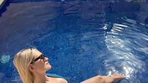 A person sitting by a pool with clear blue water.