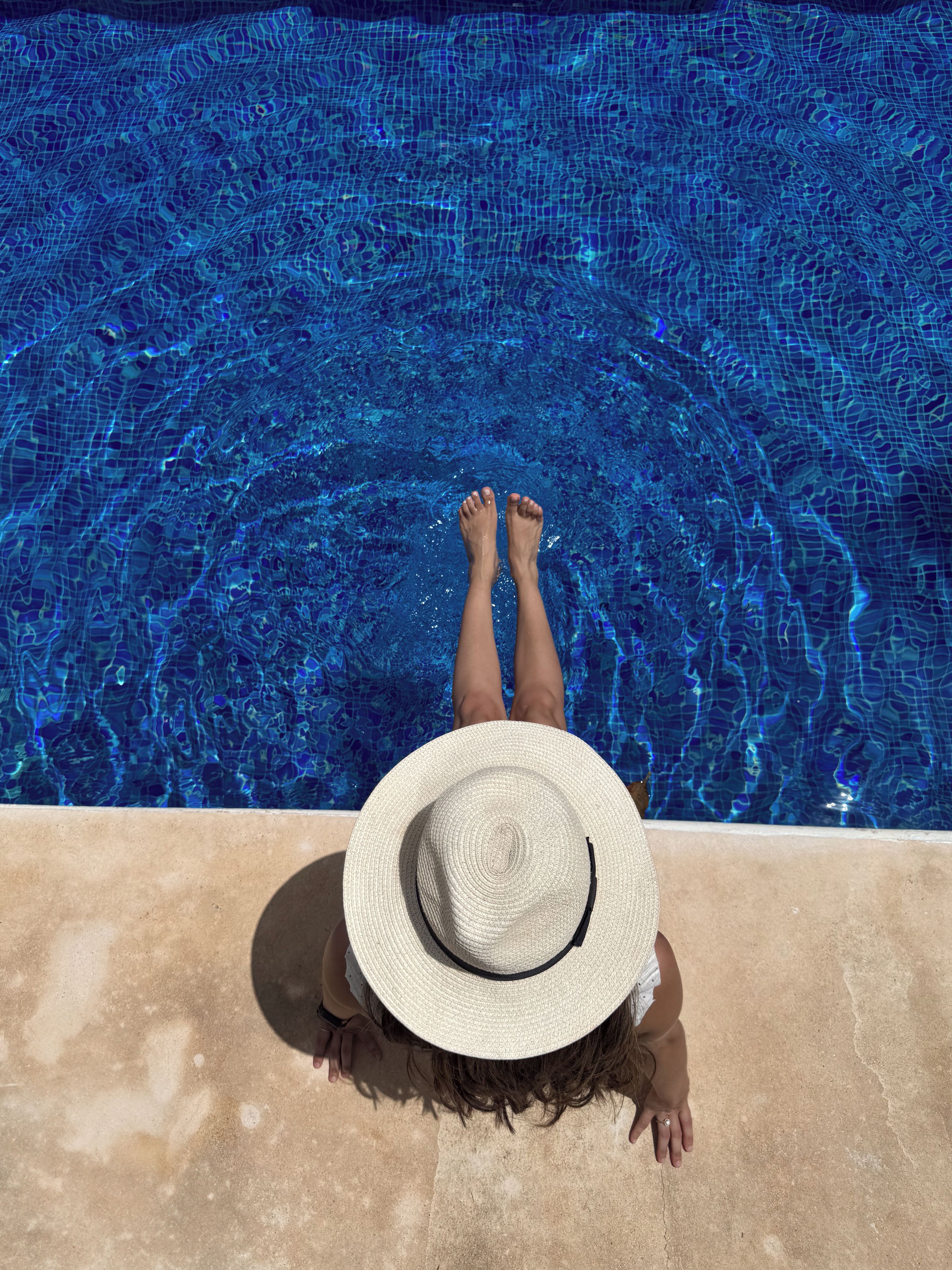 A person relaxing by a swimming pool with a view of the water.
