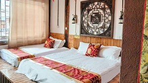 Une chambre d’hôtel avec deux lits, un plancher en bois, un élément décoratif mural et une fenêtre avec des rideaux.