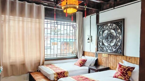 Une chambre d’hôtel avec deux lits, un plancher en bois, une grande fenêtre avec des barreaux en métal et un élément décoratif mural.