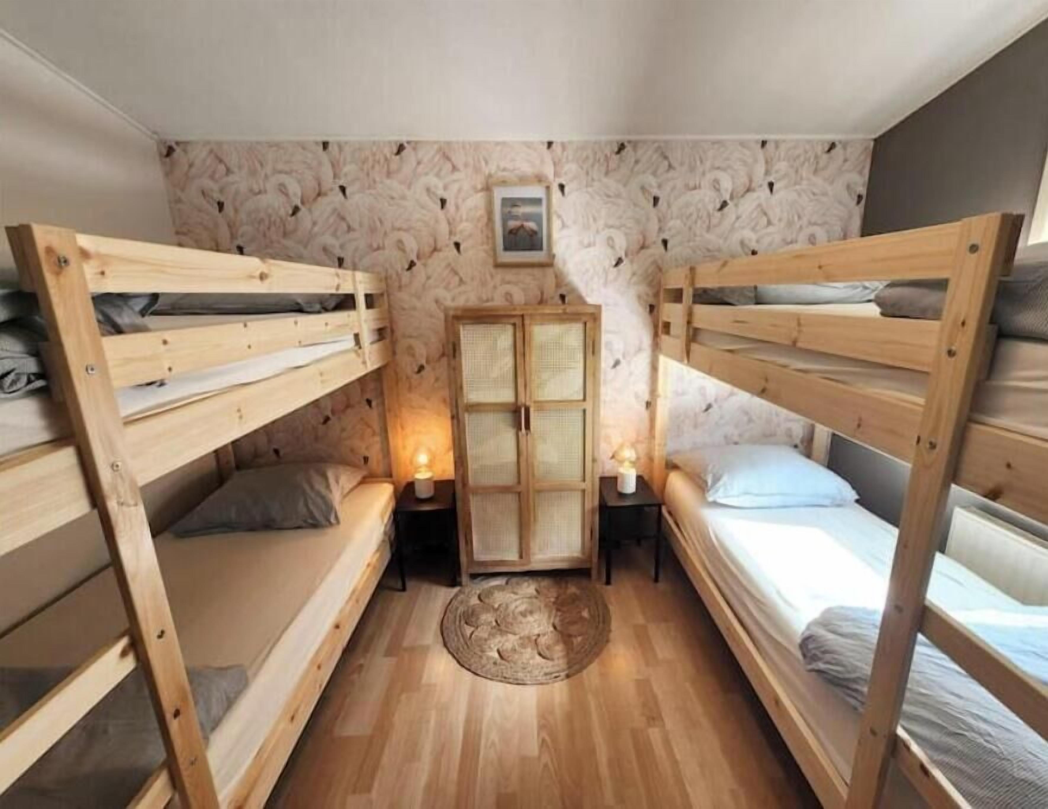 Una habitación compacta con dos literas, un mueble pequeño y una alfombra redonda sobre el suelo de madera.