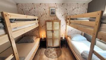 Una habitación compacta con dos literas, un mueble pequeño y una alfombra redonda sobre el suelo de madera.