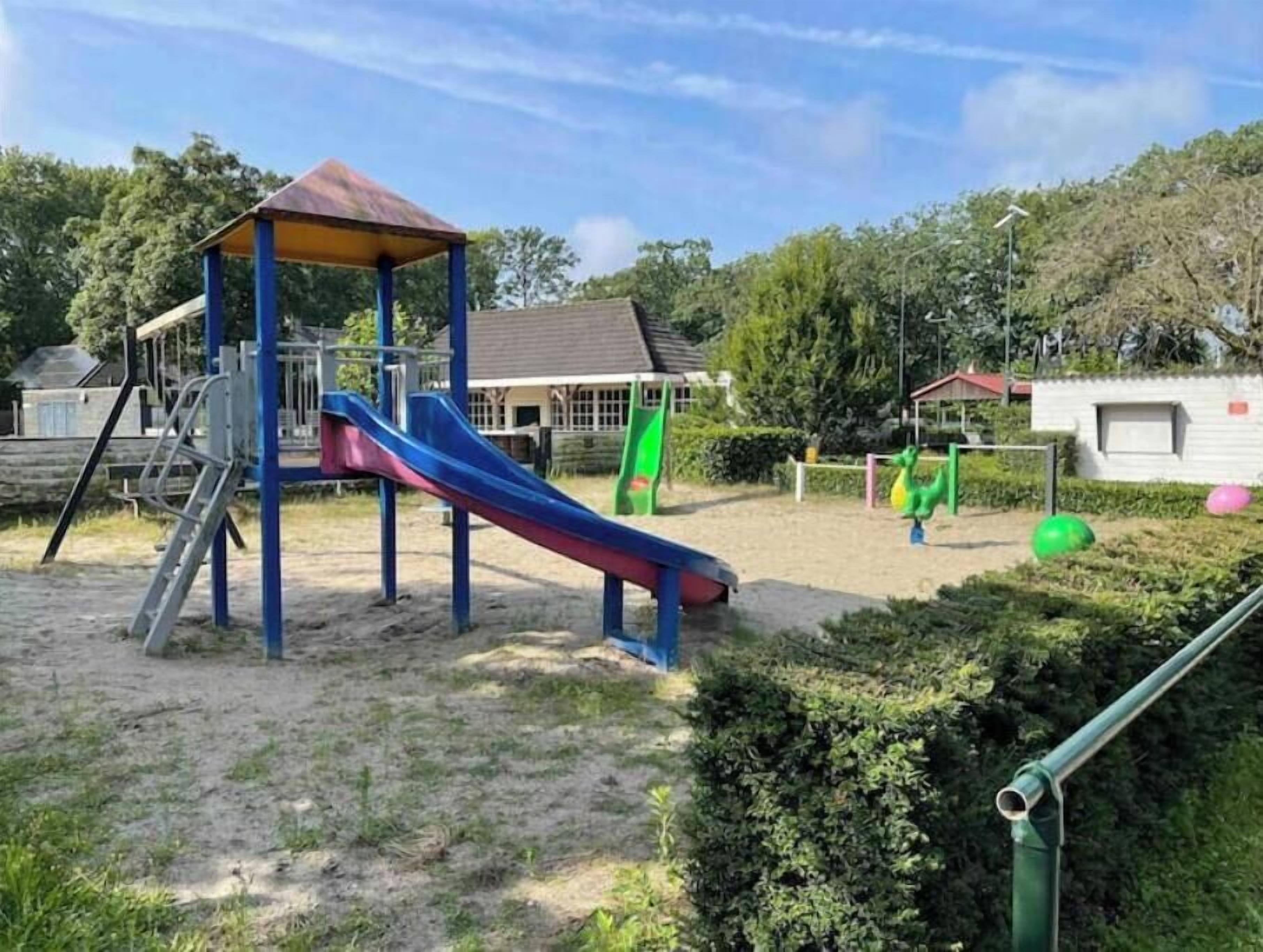 A playground with a slide, climbing structure, and a covered area.