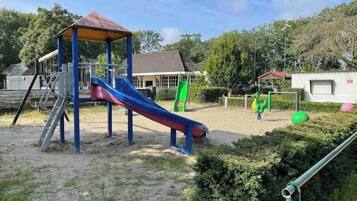 A playground with a slide, climbing structure, and a covered area.