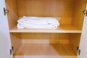 Ein Holzkabinent mit einer Ablage, auf der gefaltete weiße Handtücher liegen.