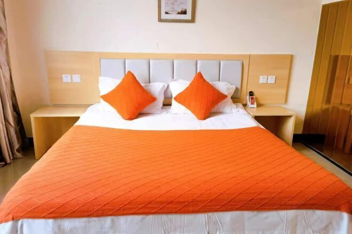A hotel room with a bed, two nightstands, and a wooden headboard.