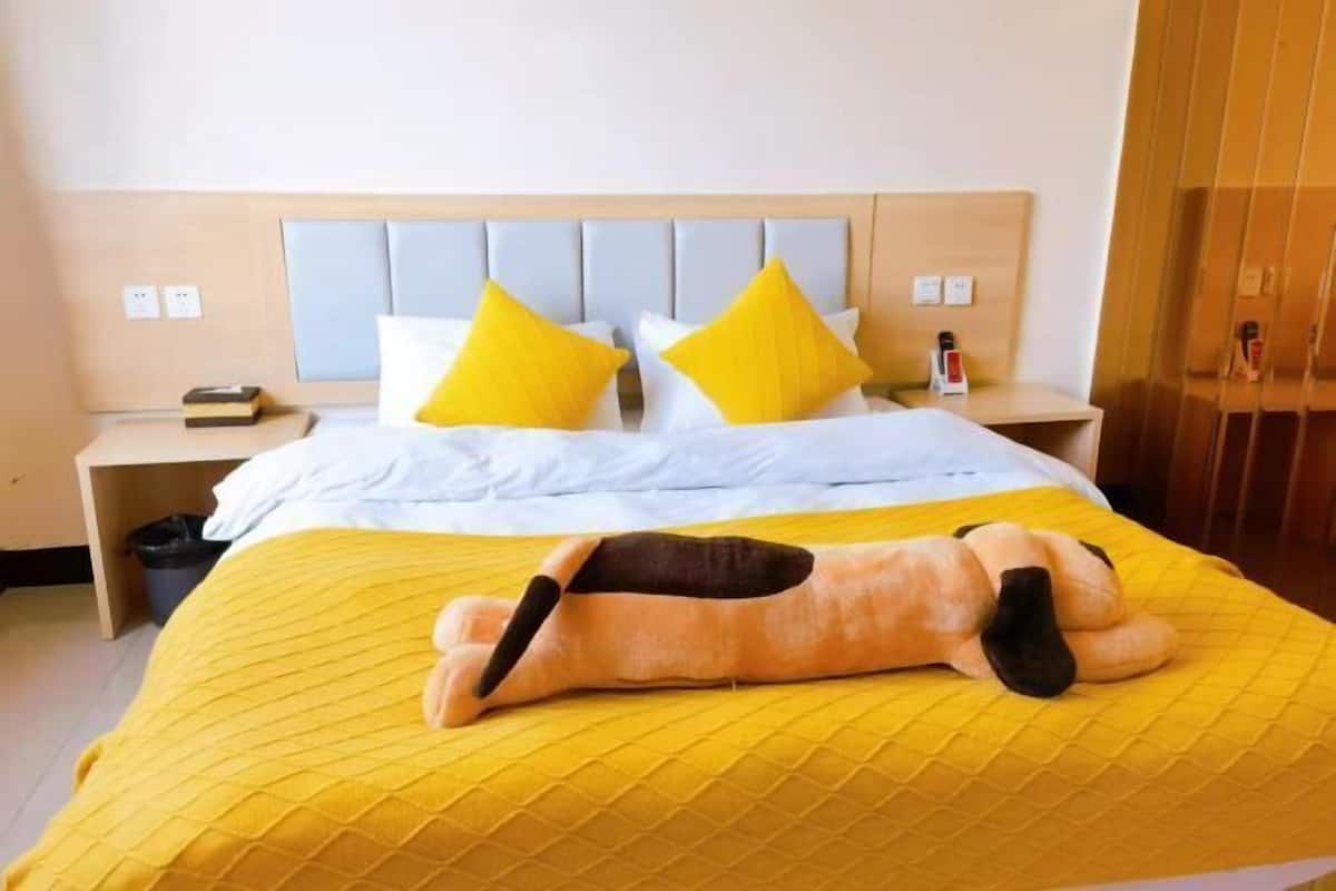 A hotel room with a bed, a nightstand, a lamp, and a wooden headboard.