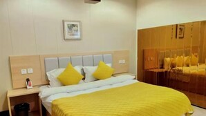 A hotel room with a bed, a nightstand, a trash bin, and a wooden wardrobe. - Nanwang Hotel (Shanghai Fengxian University Town) (Shanghai)