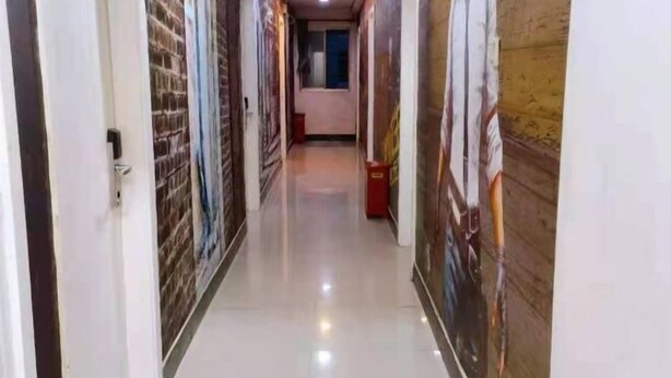 A corridor with a tiled floor and walls adorned with artwork. - Nanwang Hotel (Shanghai Fengxian University Town) (Shanghai)