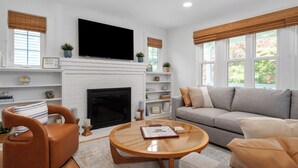 Una sala de estar con chimenea, televisor, sofá y una mesita de centro.
