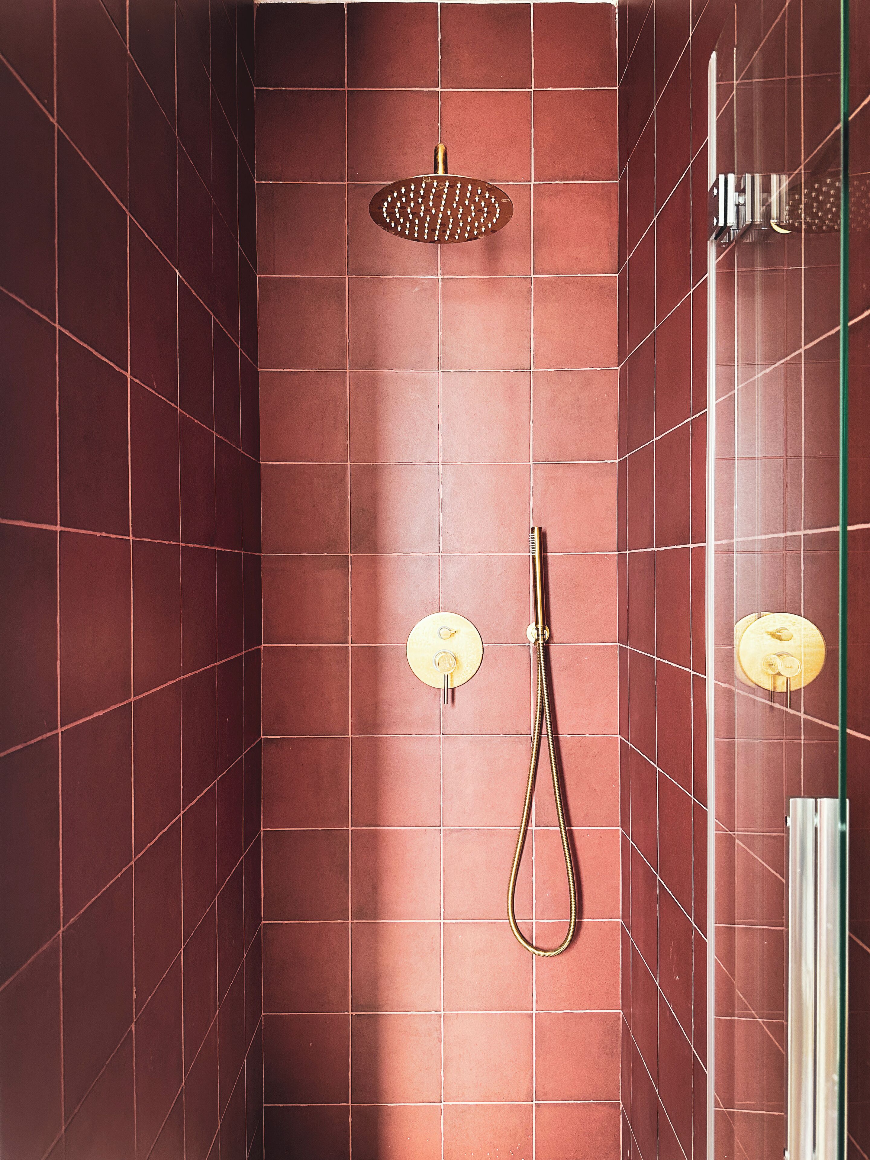 Un espace douche équipé d’un pommeau de douche à main et d’une douchette à pluie fixée au mur.