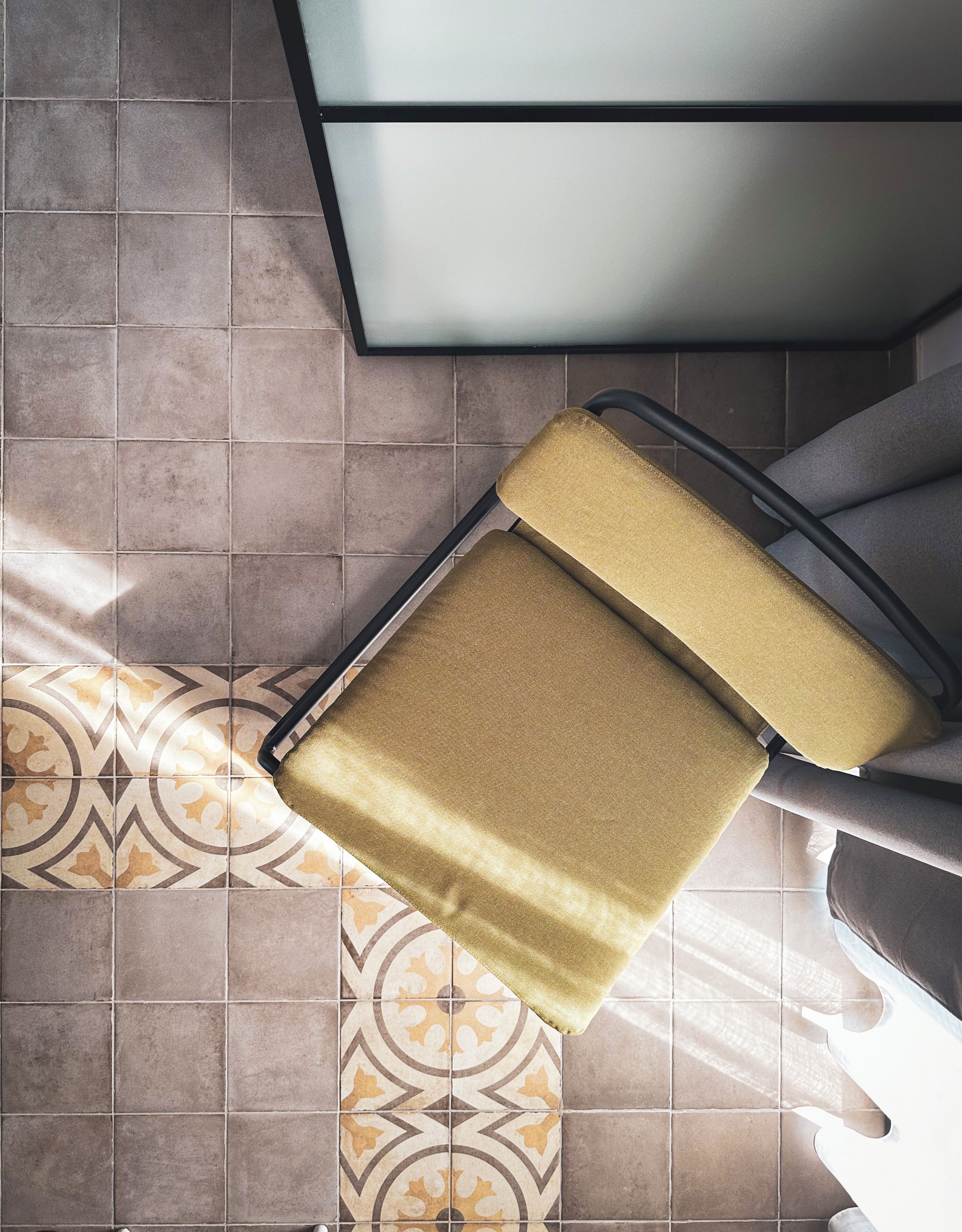 A chair with a metallic frame and a textured seat, placed on a patterned floor.
