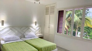 A bedroom with two beds, a wardrobe, and a window with a view of palm trees. - Family Home: Your Couzy Refuge in Same with Pool and 7 Beds! (Altos del Mar)