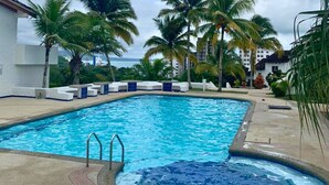 A swimming pool with a hot tub, surrounded by palm trees and a view of a building. - Family Home: Your Couzy Refuge in Same with Pool and 7 Beds! (Altos del Mar)