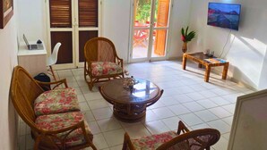 A room with a round table, wicker chairs, a TV, and a window with shutters. - Family Home: Your Couzy Refuge in Same with Pool and 7 Beds! (Altos del Mar)