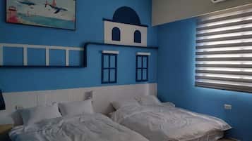 Una habitación con dos camas, una pared azul, una ventana con persianas y un cuadro.