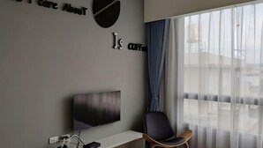 Une chambre moderne dotée d’une grande fenêtre, d’un téléviseur à écran plat, d’un bureau et d’une chaise.