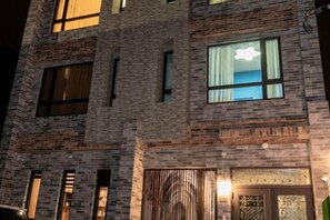 Un edificio de varios pisos con fachada de ladrillo, ventanas amplias y una puerta con paneles de vidrio decorativos.