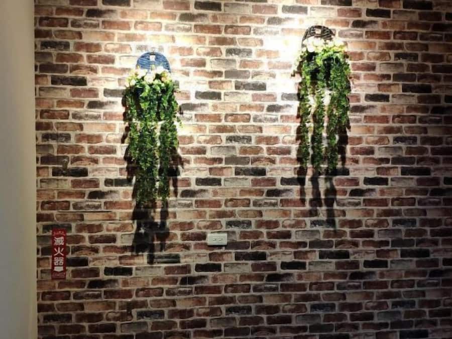 Una pared de ladrillo con dos adornos colgantes verticales.