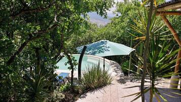 Un área de piscina con una sección cubierta, rodeada de exuberante vegetación y vistas despejadas del paisaje.