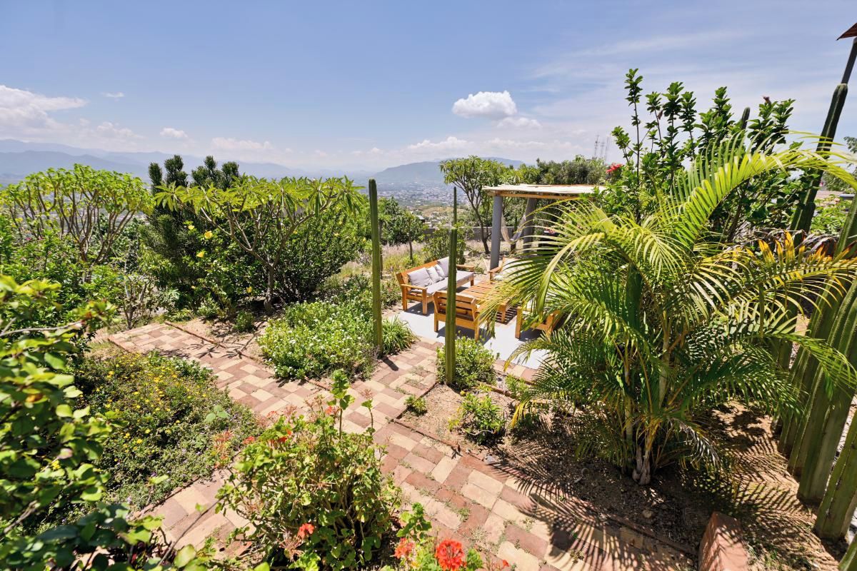 Un jardín con un pérgola, zona de estar y vistas a montañas distantes.