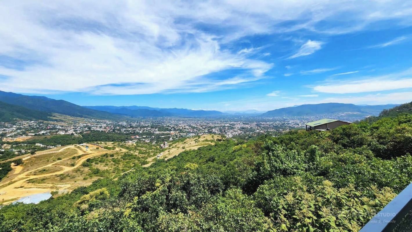 A panoramic view of a city from a hilltop with a clear sky.