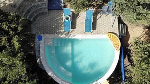 Ein Swimmingpool mit einem sechseckigen Fliesenbelag, umgeben von Liegestühlen und einem Sonnenschirm.