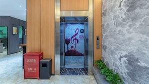 An elevator with a musical note design, a red box with text, and a marble floor. - Ease Hotel (South Ningbo CBD Romon World Park Store, BTG Homeinns) (Ningbo)